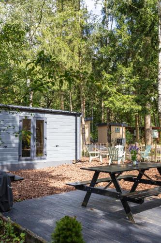 a picnic table in front of a cabin at Schitterend chalet in het bos in Doornspijk