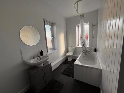 un bagno con un lavandino, una vasca e uno specchio di Just Stay 2 a Warrington