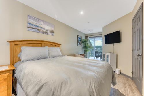 um quarto com uma cama grande e uma televisão em Oceanside GetAway at Pacific Shores em Nanoose Bay