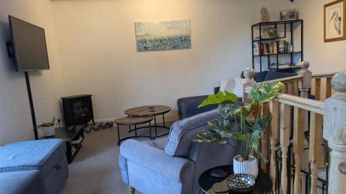a living room with a blue couch and a tv at The Owlery Alnwick in Alnwick
