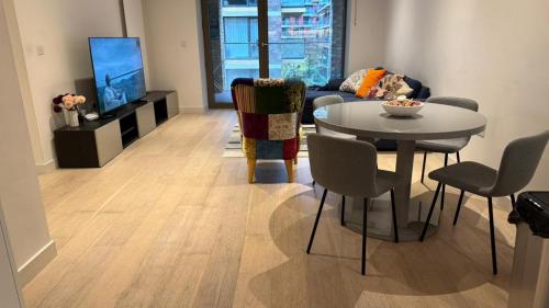 a living room with a table and a tv at Silvertown Luxe Living in London