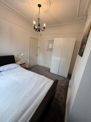 a bedroom with a large white bed and a chandelier at London Cozy Room, Fast WiFi in London