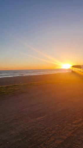 a sunset on a beach with the sun setting at Apartamento Isla de Margarita in Pampatar