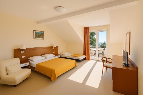 Un dormitorio con cama, escritorio y televisión. en Hotel Neptun Gradac, en Gradac