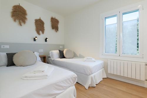 een witte kamer met 2 bedden en een raam bij Apartamento Rosari II in Vilassar de Mar