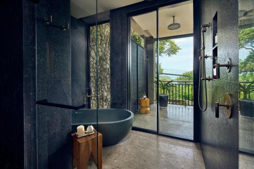 a bathroom with a large tub and a glass door at Nekajui Peninsula Papagayo, a Ritz-Carlton Reserve in Papagayo, Guanacaste
