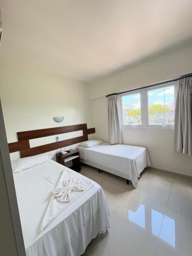 a hotel room with two beds and a window at Hotel Boa Vista - 200mts do Shopping Pátio in Chapecó