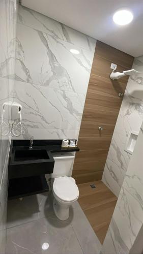 a bathroom with a toilet and a marble wall at Hotel Ellos - Estacionamento e Café da Manhã Incluso in Itaquaquecetuba