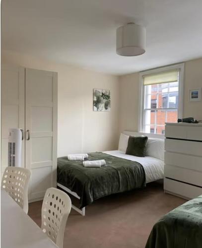a bedroom with a bed and two chairs and a window at Lovely Rooms in Camden Town, Central London in London