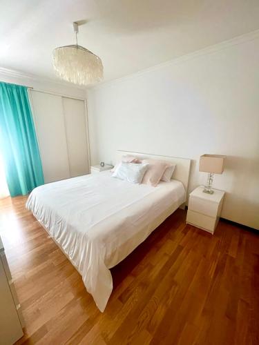 a bedroom with a large white bed and a chandelier at Rodamar Apartment Forum Funchal in Funchal