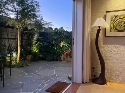 a door to a patio with a floor lamp and a patio at Cosy Cottage in North Fitzroy in Melbourne
