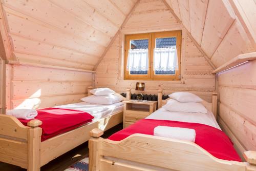 twee bedden in een houten kamer met een zolder bij udanypobyt Dom Bright House in Kościelisko