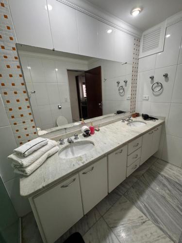 une salle de bains avec deux lavabos et un grand miroir dans l'établissement Flat no coração de Alphaville, à Barueri