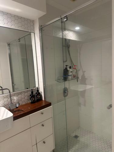 a bathroom with a glass shower and a sink at Beautiful rooms in An Apartment Free Parking in Brisbane