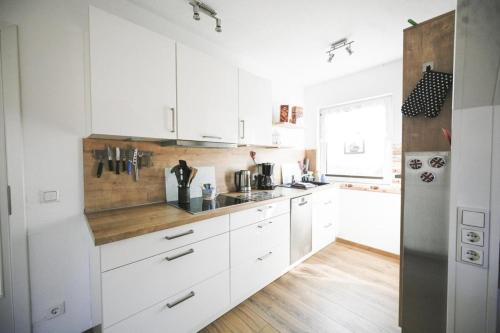 巴尔特鲁姆Haus Deichbrise的配有白色橱柜和木质台面的厨房