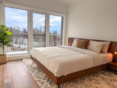 a bedroom with a large bed and large windows at Oso Skyview Suite - DT modern 2 bed, 2 bath in Golden