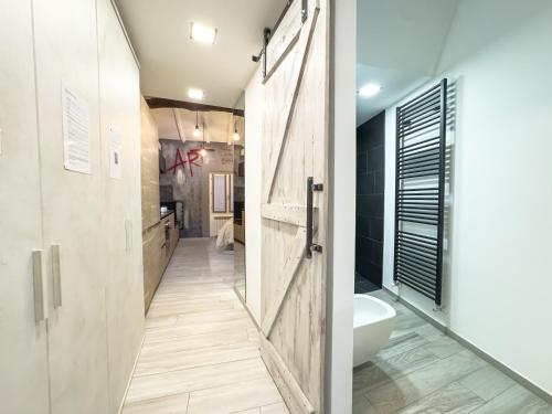 a bathroom with a wooden door and a white toilet at Centro storico- Suite silenziosa, Wi-Fi & Netflix in Varese