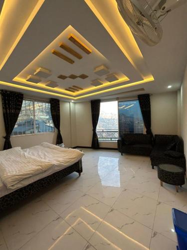 a bedroom with a bed and two chairs and windows at Askari Lodges Murree in Murree