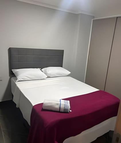 a white bed with a bottle and a towel on it at Apto elegante no Catolé 28 in Campina Grande