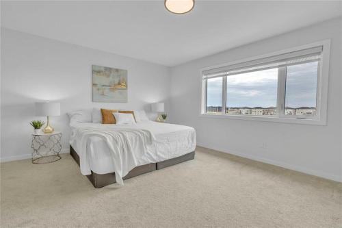 um quarto branco com uma cama e uma janela em Lakeview at Prairie Pointe em Winnipeg