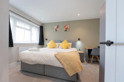 een slaapkamer met een groot bed met gele kussens bij Modern High Spec Home in Titsey