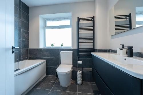 een badkamer met toilet, bad en wastafel bij Modern High Spec Home in Titsey