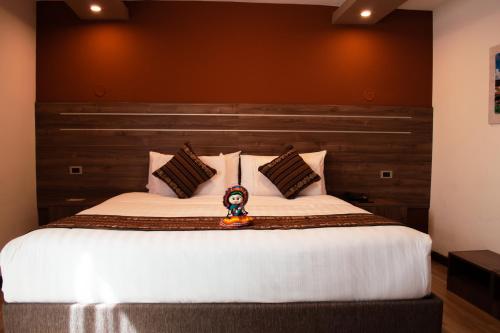 Un dormitorio con una cama grande con un juguete. en INKALAM cusco, en Cusco