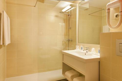 a bathroom with a sink and a shower and a mirror at Kyriad Hotel Strasbourg Lingolsheim in Lingolsheim