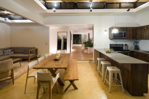 a kitchen and living room with a wooden table and chairs at Nalu Nosara Pool Villa Jardin in Nosara
