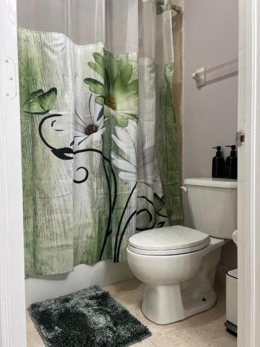 a bathroom with a toilet and a flower shower curtain at Vacation QJR in Cutler Bay