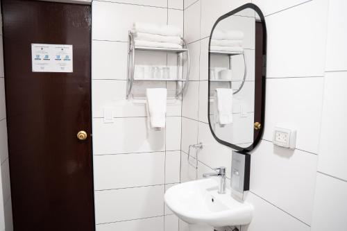 Un baño blanco con lavabo y espejo. en Hotel Cusco Plaza Saphi, en Cusco