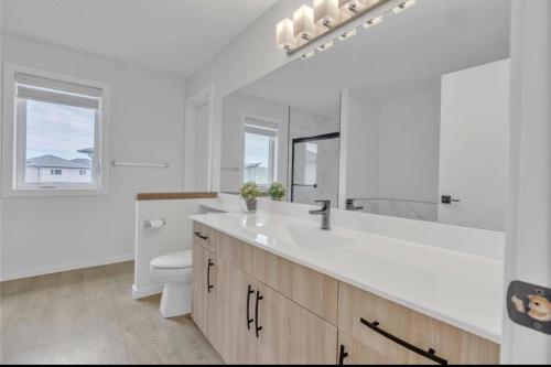 um banheiro branco com uma pia e um vaso sanitário em Lakeview at Prairie Pointe em Winnipeg