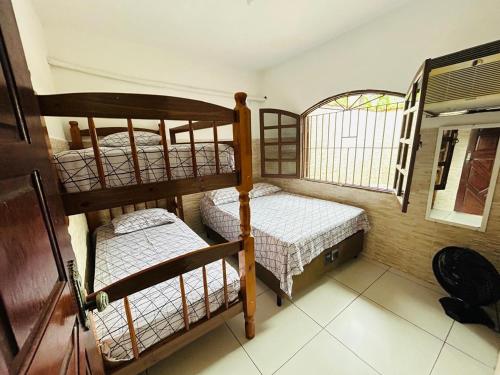 two bunk beds in a room with a window at Casa em Bertioga com piscina aquecida Sitio família ROCHA in Bertioga