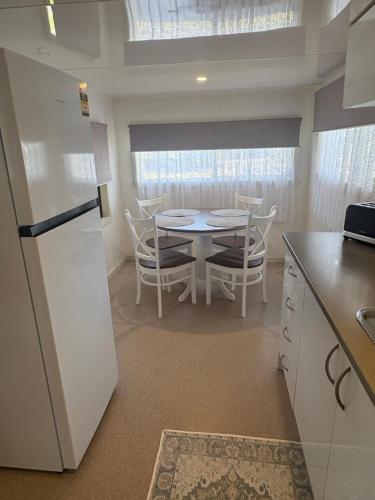 a kitchen with a white refrigerator and a table with chairs at Turners Beach Holiday Cabin in Turners Beach