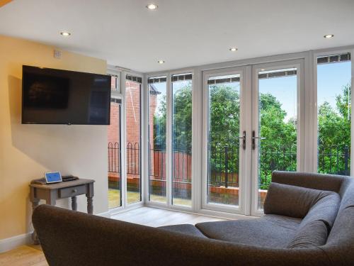 Song Bird Holiday Home في ويتبي: غرفة معيشة مع أبواب زجاجية منزلقة وأريكة