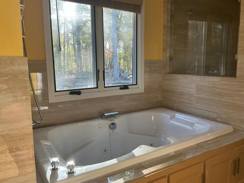 a large bath tub in a bathroom with a window at Quiet Forest Vacation home on a Private Road with Spacious Patios, Fire pit, Pet friendly and a Private pool in Tullahoma