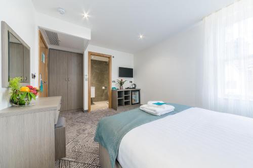 a bedroom with a large white bed and a bathroom at The Lion & Key Hotel in London