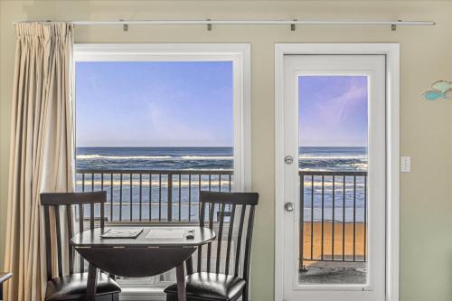 a balcony with a table and chairs and a view of the ocean at Ground Floor Fireplace Studio - Ocean View & Beach Access - Pool and Hot Tub in Lincoln City