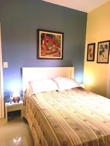 a bedroom with a bed with a painting on the wall at Casa temporada perto do centro in Garopaba
