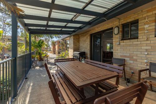 an outdoor patio with a wooden table and benches at Sandcastle 7 with WiFi in Tuncurry