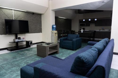 een woonkamer met een bank, stoelen en een tv bij Departamentos Arista in Oaxaca City