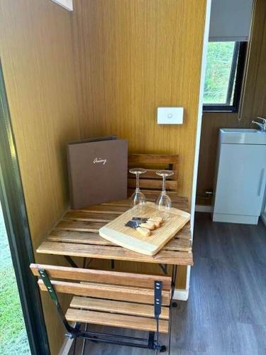 a table with two wine glasses and a box on it at The Stables by Tiny Away in Palmwoods