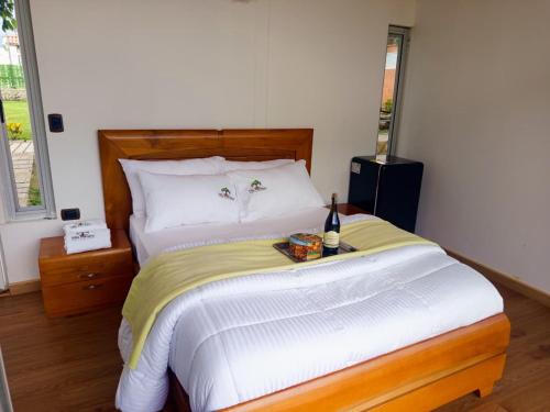 Un dormitorio con una cama con una botella de vino. en Cabaña Colibrí Silvania Cundinamarca, en Silvania