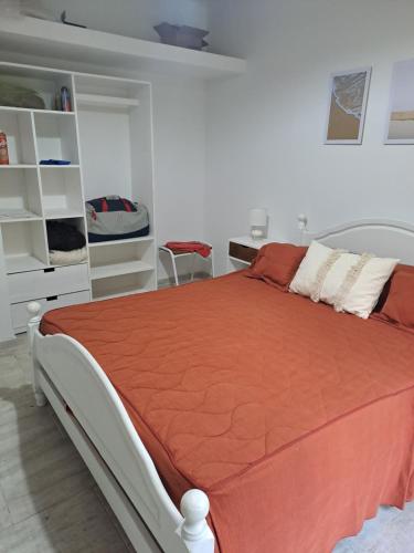 a bedroom with a bed with an orange comforter at Casa de Andres in Ataliva Roca