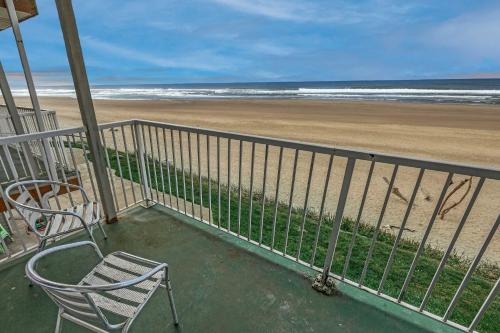 a balcony with two chairs and the beach at Oceanfront Suite - Sleeps Six - Pool & Hot Tub in Lincoln City