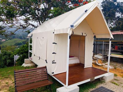 a white tent with a bench in a yard at Cabaña tipi Ardilla Silvania Cundinamarca in Silvania