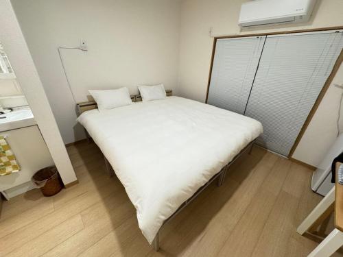 a small bedroom with a large white bed in it at Ippaku 一泊 in Izumi-Sano