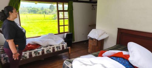 una mujer parada en un dormitorio con dos camas en Lodge Chagras y Arrieros, 