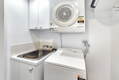 a small kitchen with a sink and a stove at Poolside Bliss in Maroochydore