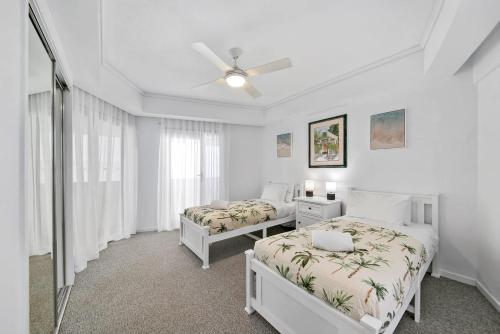 a bedroom with two beds and a ceiling fan at Poolside Bliss in Maroochydore